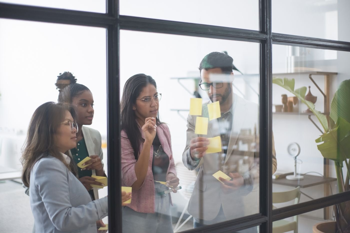 Équipe en atelier de cadrage collant des post-it sur une paroi vitrée