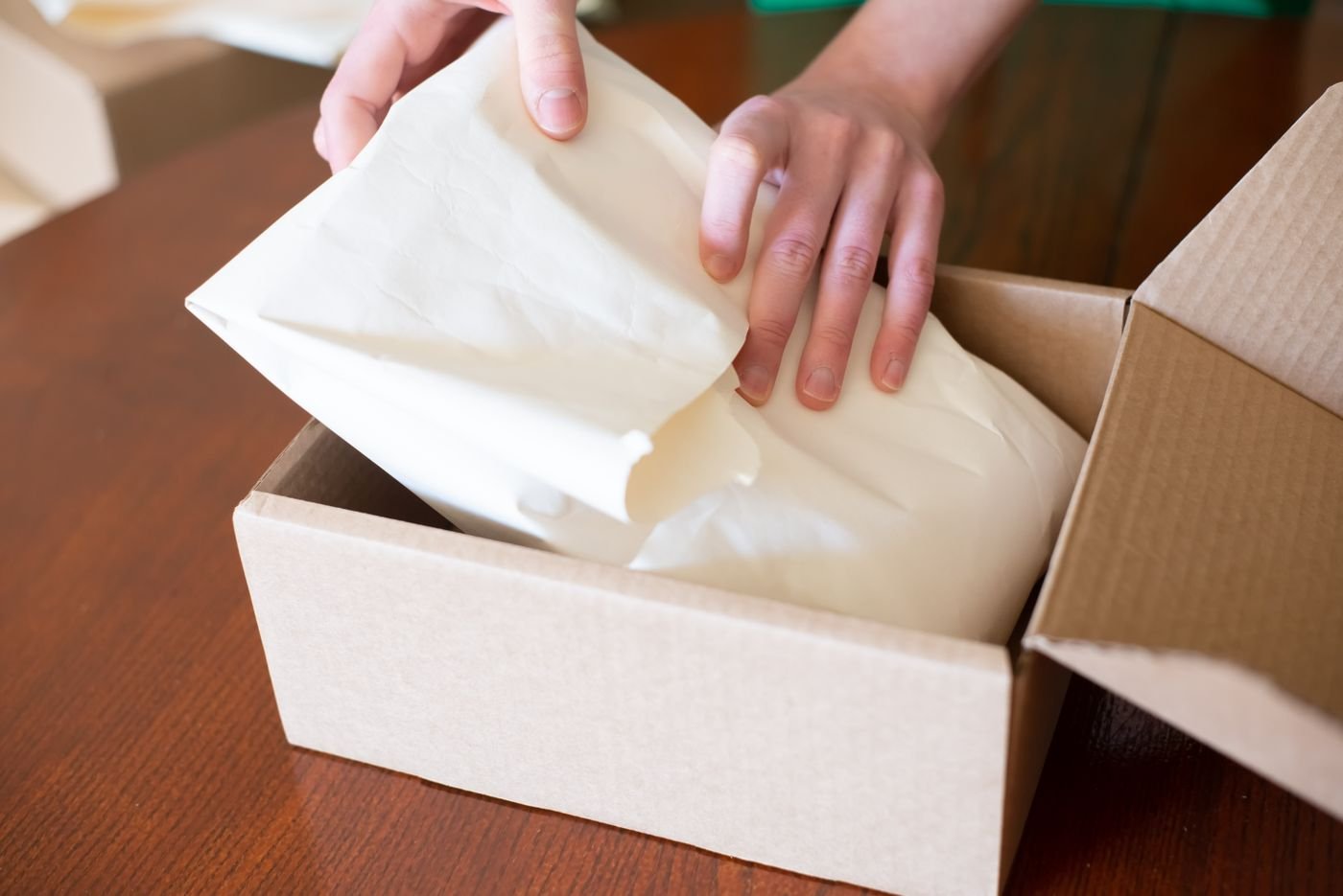 Préparation d’une commande e-commerce : un produit emballé dans du papier de soie déposé dans un carton