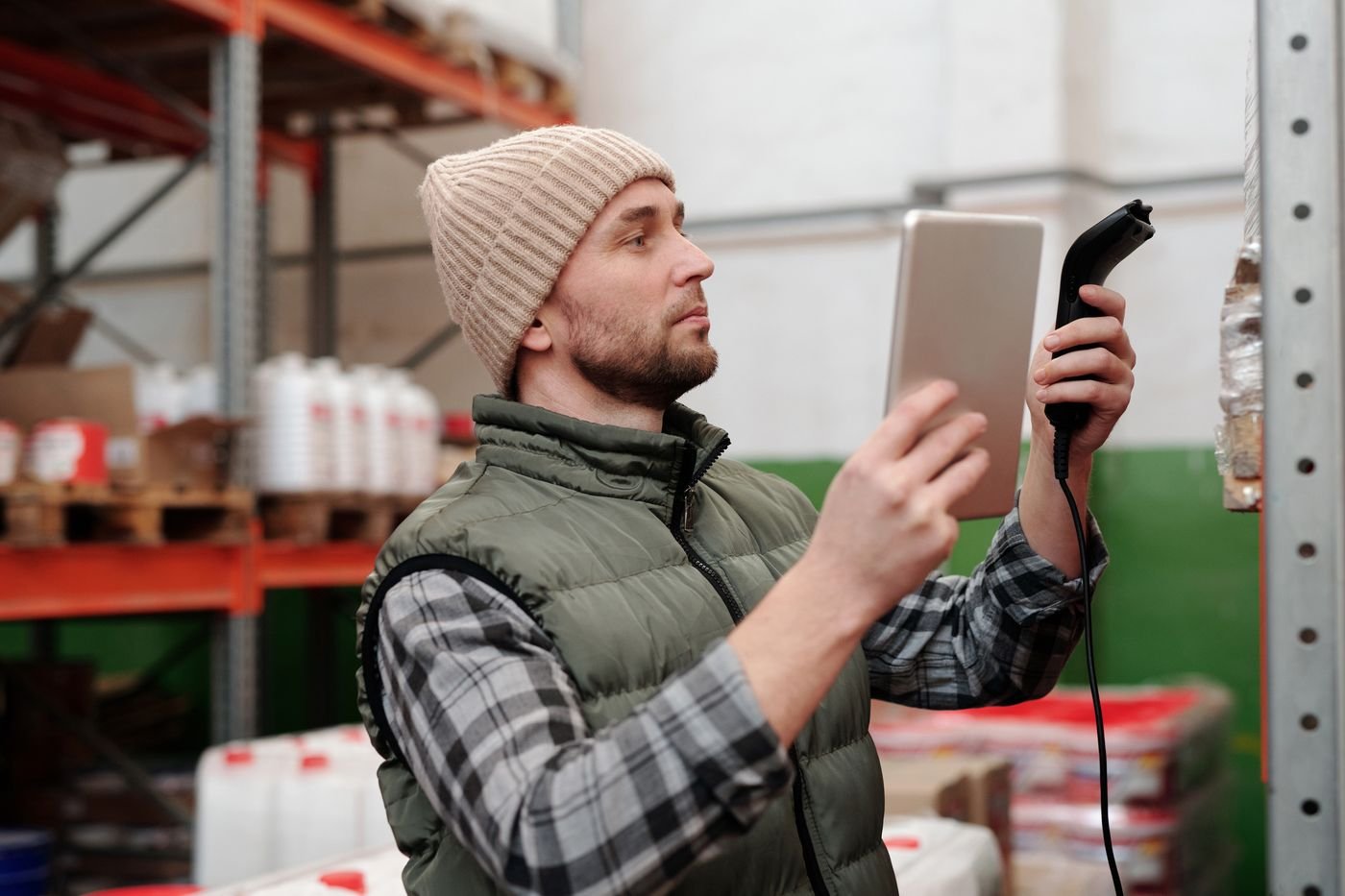 Préparateur de commandes vérifiant le stock sur une tablette avec un scanner dans un entrepôt logistique